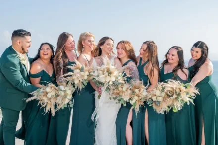 Pure joy and genuine laughter shared among life's truest friends. Wrapped in deep emerald hues against the clear tropical sky, this candid moment captures the warm connection and heartfelt love surrounding the bride on her special day in Puerto Vallarta