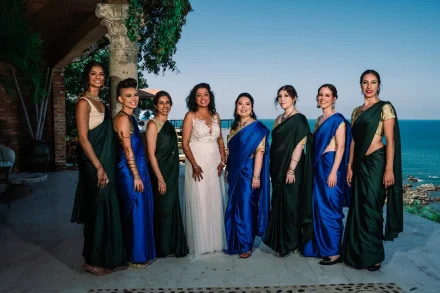 Surrounded by love, beauty, and lifelong friendship. Framed by sweeping ocean vistas, the bride stands radiant among her closest companions, each elegantly dressed in vibrant traditional saris for a truly unforgettable destination wedding in Puerto Vallarta