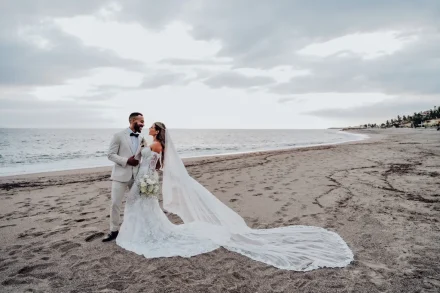 A timeless gaze filled with unconditional love and promise. Standing along the serene shoreline with her long train sweeping gracefully across the sand, the newlyweds share a peaceful, unforgettable moment in Puerto Vallarta