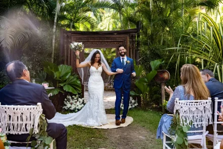 Pure excitement as they take their first steps together as husband and wife! Cheered on by cheering guests, the bride triumphantly raises her bouquet as she walks down the aisle with her groom through a lush tropical garden in Puerto Vallarta