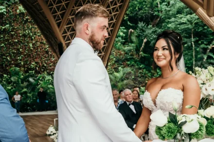 Medium shot of the bride and groom holding hands and looking lovingly at each other during their wedding ceremony