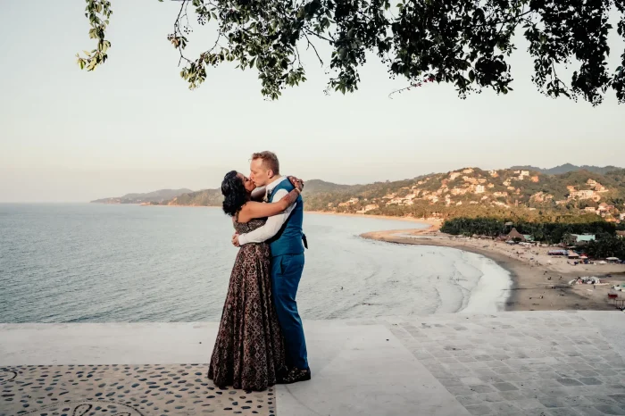 Standing high above the coast where the ocean whispers to the shore, wrapped tightly in an embrace that feels like coming home. A breathtaking, panoramic kiss captured high above Puerto Vallarta—a pure statement of romantic elegance and everlasting devotion
