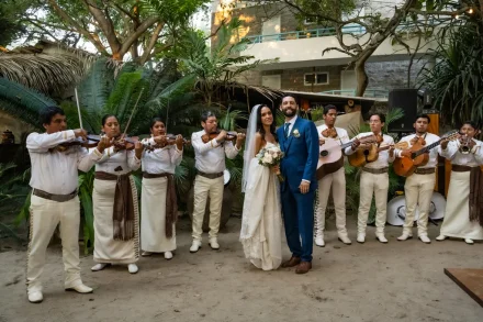 A festive celebration filled with rich tradition and joyous melodies. The happy couple poses happily in the center as a full mariachi band plays around them, filling the tropical garden with vibrant energy in Puerto Vallarta