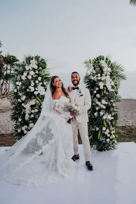 Radiant, proud, and deeply connected. Framed by lush tropical foliage and pristine white orchids, the newly married couple poses on the shoreline, capturing the pure bliss of their unforgettable beach wedding in Puerto Vallarta