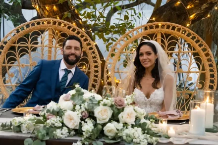 Radiant smiles at their sweetheart table! Sitting side-by-side in beautiful wicker peacock chairs framed by twinkling lights and elegant florals, the newlyweds enjoy a comfortable and joyous moment together during their reception in Puerto Vallarta