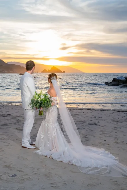 Taking a quiet moment to gaze at the horizon together. As the sun sets over the ocean and the gentle breeze carries the magic of the day, standing side by side marks the peaceful beginning of your forever