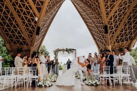 Pure, cinematic joy. After promising forever, the couple celebrates with an unforgettable kiss while their loved ones burst into applause beneath the stunning open-air chapel architecture