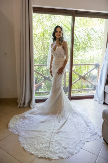 Elegance and anticipation in its purest form. Standing gracefully before the natural light of a sliding balcony window, the bride shines in her detailed lace gown and veil, preparing to step into the most memorable chapter of her life in Puerto Vallarta