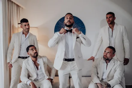 Sharply dressed and ready for the big moment. A stylish, candid shot of the groom adding the finishing touch to his look while surrounded by his closest crew in Puerto Vallarta