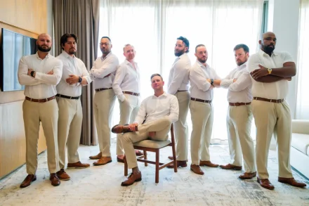 Handsome groom sitting confidently surrounded by his groomsmen in matching white shirts and beige trousers before the destination wedding ceremony in Puerto Vallarta