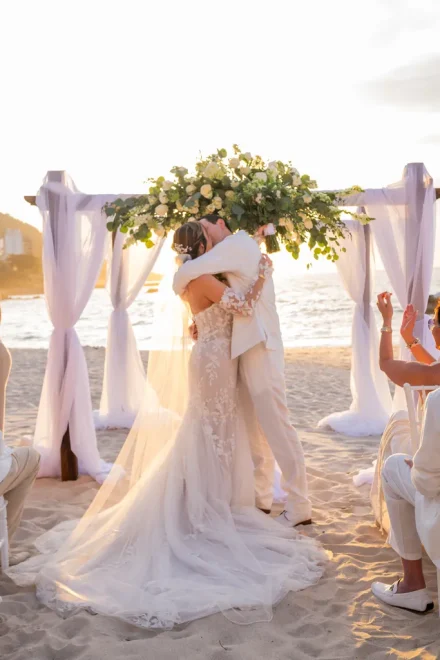 The defining moment where time stands still. Wrapped in the golden sunset glow with the soft sound of waves in the background, your first kiss as husband and wife beneath the arch becomes the unforgettable beginning of your forever story