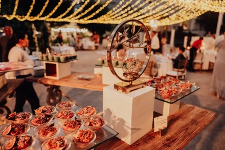 A magical culinary display under a canopy of warm twinkling lights. An exquisitely detailed dessert table setup that welcomes guests to indulge and celebrate an unforgettable night in Puerto Vallarta