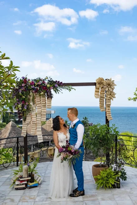 A quiet world made just for two. Embraced under a floral arch as blue skies meet the calm Pacific, their gaze holds the deep promise of a lifetime spent together in beautiful Puerto Vallarta