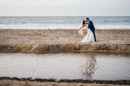 A breathtaking cinematic moment by the sea! With the horizon stretching wide and soft waves breaking behind them, the groom dips his bride for a passionate kiss on the shores of Puerto Vallarta—a timeless memory frozen in pure romance