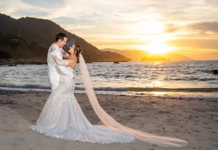 As the golden sun dips into the ocean, time slows down for a breathtaking moment. With the veil sweeping gently across the sand and warmth in every glance, this romantic beach portrait captures the pure magic of starting forever together