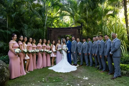 A wonderful celebration surrounded by family and close friends. Flanked by their loved ones in matching pink gowns and classic grey suits, the newlyweds pose together in a lush, palm-filled paradise in Puerto Vallarta