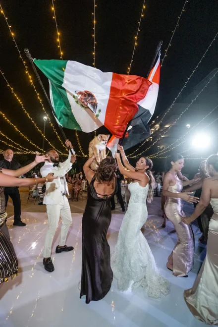 Unbridled joy, vibrant culture, and unforgettable memories! The newlyweds and their guests celebrate on the dance floor waving flags and lifting their beloved pet, creating a uniquely festive and lively highlight of their wedding reception in Puerto Vallarta