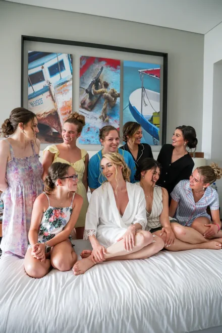 Laughter, excitement, and cherished morning moments. Surrounded by her closest friends and family during wedding prep, the bride shines in a white silk robe—capturing the candid joy and intimacy before stepping into her dress in Puerto Vallarta