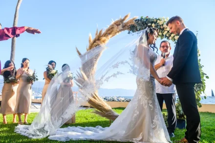 A sacred moment of union framed by coastal sunshine and the gentle sea breeze. Holding hands beneath a delicate pampas grass arch while receiving a loving blessing creates an atmosphere of deep emotion and profound connection during your Puerto Vallarta wedding ceremony