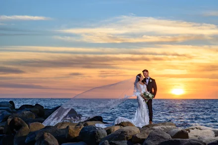 A breathtaking symphony of light, land, and love. Standing together on the coastal rocks as the glowing sun touches the ocean horizon, this serene sunset portrait captures pure romantic serenity in Puerto Vallarta