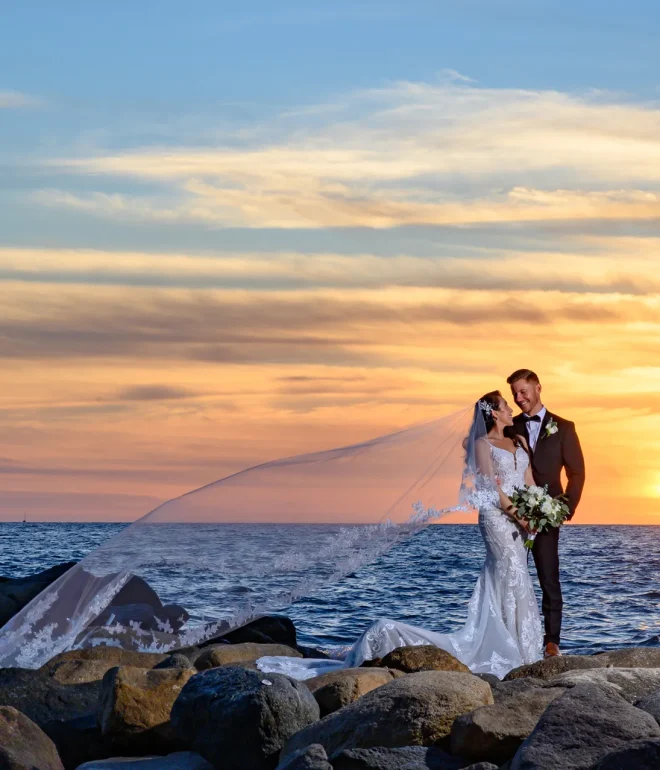 A breathtaking symphony of light, land, and love. Standing together on the coastal rocks as the glowing sun touches the ocean horizon, this serene sunset portrait captures pure romantic serenity in Puerto Vallarta