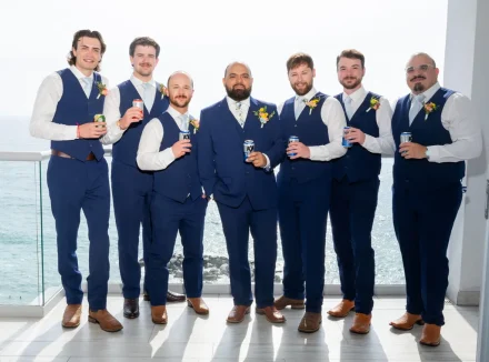 A stylish pre-ceremony toast over ocean views. Surrounded by his groomsmen in matching navy attire, the groom enjoys a relaxed moment of camaraderie and celebration high above the Pacific coastline in Puerto Vallarta
