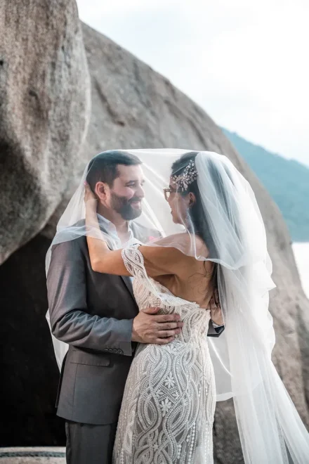 A quiet world wrapped in sheer white tulle. Sharing a tender look hidden beneath the veil creates a breathtaking, intimate portrait that captures the raw, quiet romance of your Puerto Vallarta wedding day