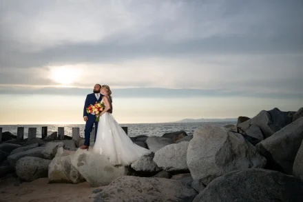Standing together at the edge of the sea as golden hour softens into dusk. Perched upon rugged coastal rocks with the ocean breeze in the air, this dramatic portrait captures timeless romantic poise and the breathtaking beauty of Puerto Vallarta