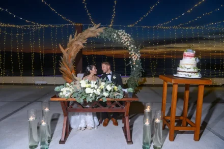 Under a canopy of twinkling fairy lights and a twilight sky over the ocean. Seated together at a beautifully adorned sweetheart table beside your wedding cake, this intimate reception moment captures the cozy romance and magic of your Puerto Vallarta evening celebration