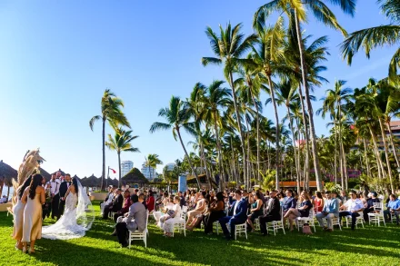 Bathed in golden coastal sunlight under a magnificent canopy of swaying palm trees. A sweeping, tropical outdoor ceremony in Puerto Vallarta that captures the vibrant warmth, beauty, and grandeur of your wedding celebration