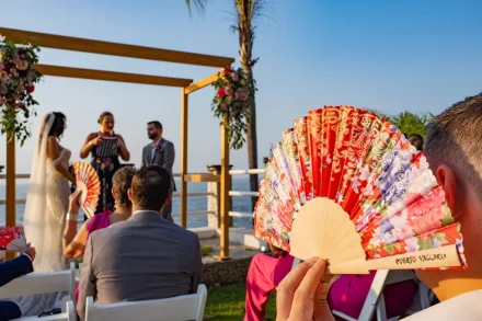 Keeping cool in the warm coastal sun while witnessing a beautiful new chapter begin. This candid moment captures a thoughtful detail that your guests will truly appreciate, adding to the charm of your destination wedding experience in Puerto Vallarta