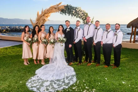 Flanked by the ones who matter most. Standing together beside the shimmering ocean framed by pampas grass and soft white blooms, this full bridal party portrait celebrates lifetime friendships and effortless destination elegance in Puerto Vallarta