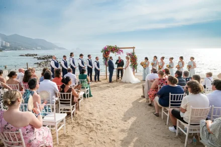 A breathtaking coastal celebration framed by sea and mountains. Surrounded by loved ones and vibrant tropical florals, the bride and groom exchange vows on the soft sands of Puerto Vallarta—a truly unforgettable setting for a destination wedding